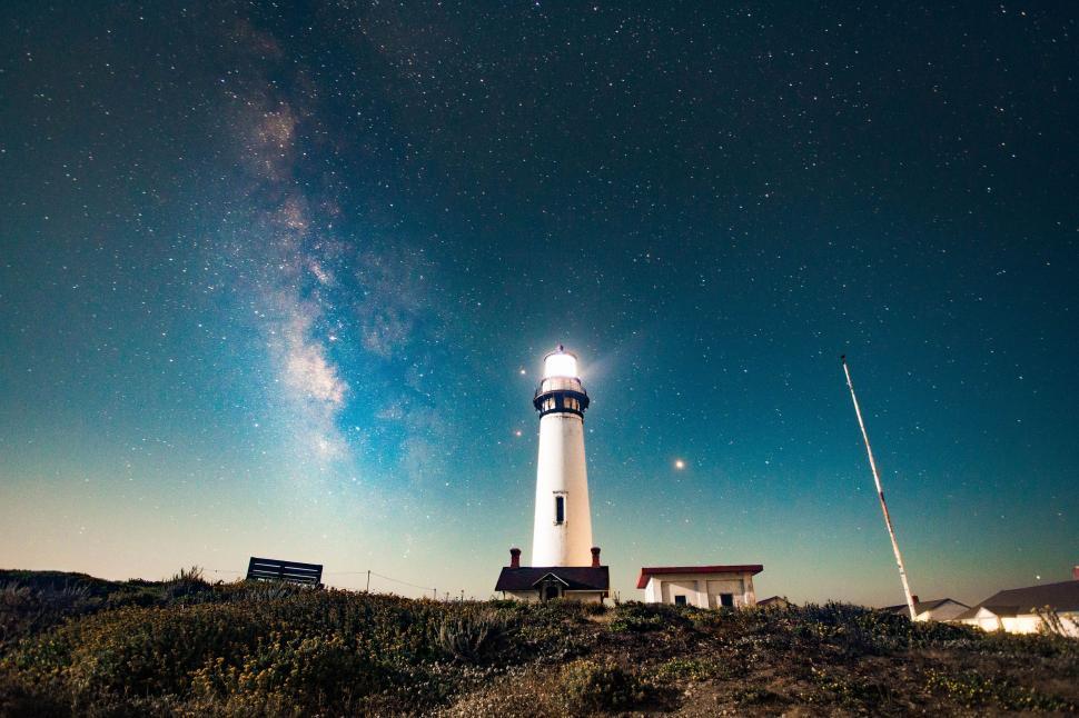 Free Image of Lighthouse Illuminating Hilltop Under Night Sky 