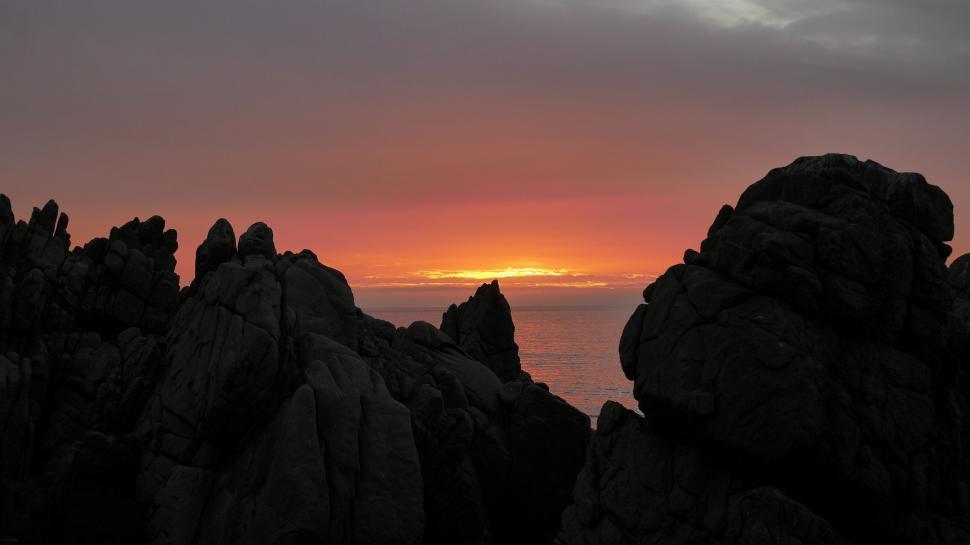 Free Image of Sun Setting Over Ocean and Rocks 