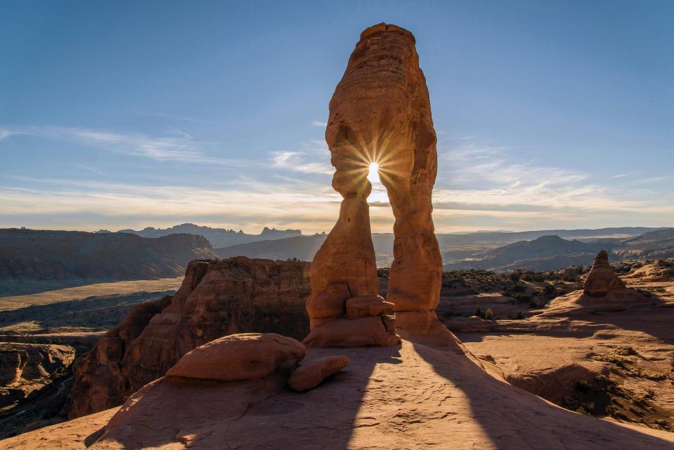 Free Image of Sun Shining Through Arch in Desert 