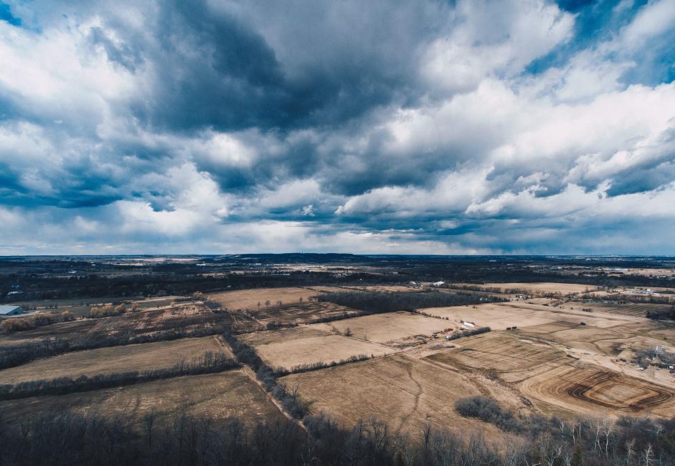 Free Image of Aerial View of Farm Land Under Cloudy Sky 