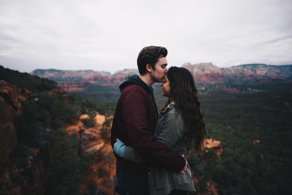 Free Image of Man and Woman Kissing in Front of Mountains 