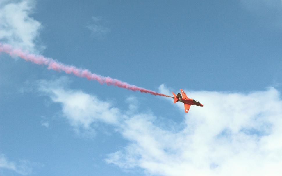 Free Image of Red and White Jet Flying Through Blue Cloudy Sky 