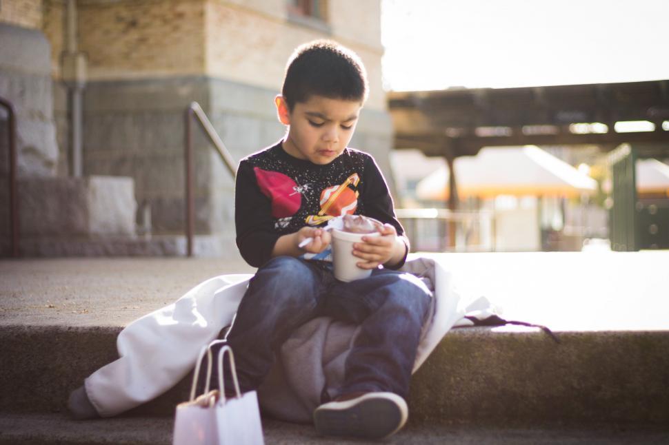 Free Image of Young Boy Sitting on Steps Holding Cup of Coffee 