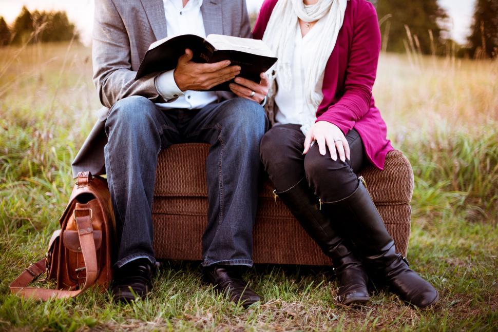 Free Image of Man and Woman Sitting on Couch Reading a Book 