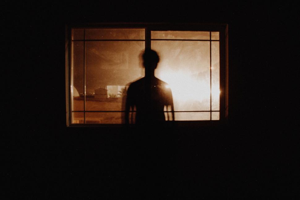 Free Image of Man Standing in Front of Window at Night 