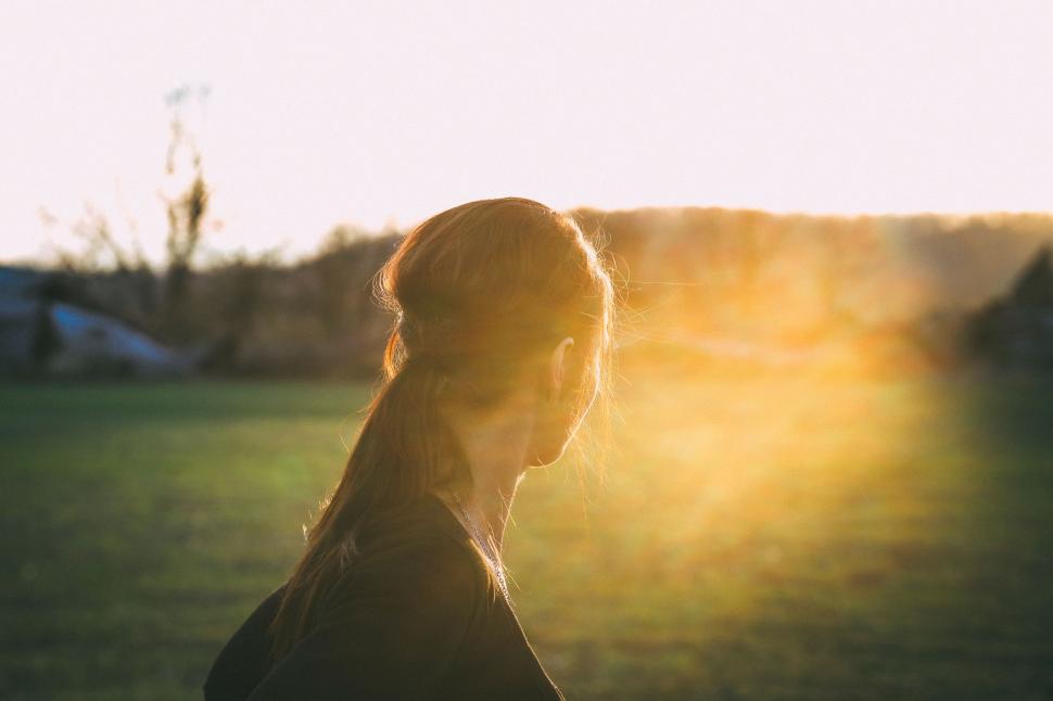 Free Image of Woman Standing in Field With Sunlight in Hair 