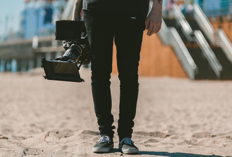 Free Image of Man Standing on Beach Holding Camera 
