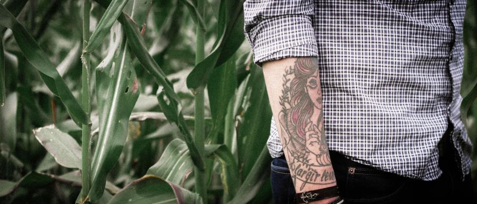 Free Image of Man With Tattoo Standing in Corn Field 