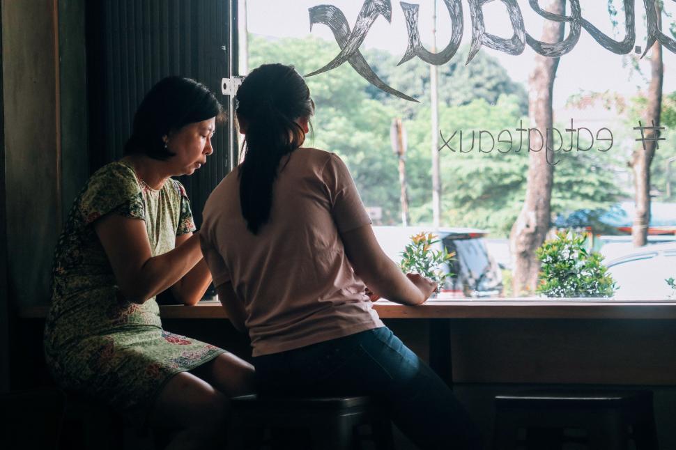 Free Image of Two Women Sitting at a Table by a Window 