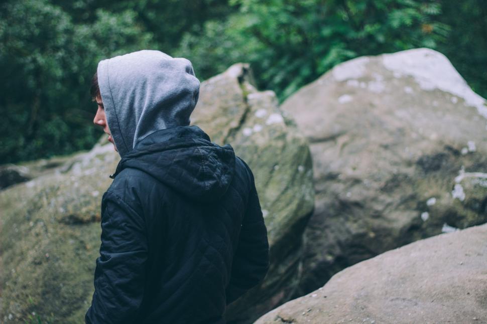 Free Image of Person in Hooded Jacket Standing in Front of Rocks 