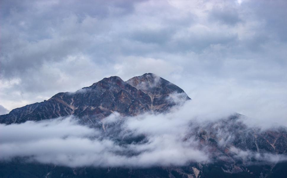 Free Image of Mountain Shrouded in Clouds Beneath Overcast Sky 