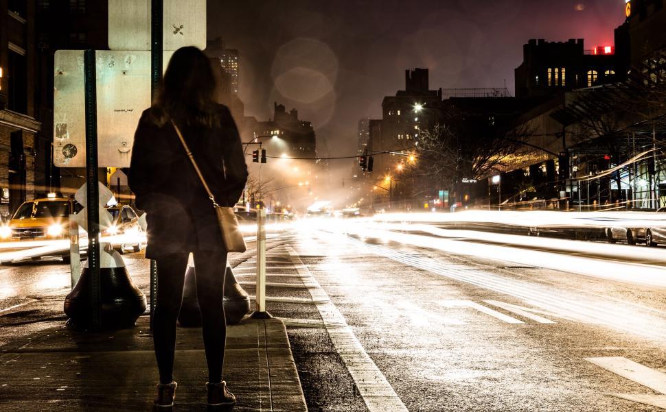 Free Image of Woman Standing on Side of Street at Night 