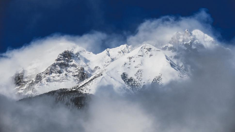 Free Image of Snow Covered Mountain With Clouds in Foreground 
