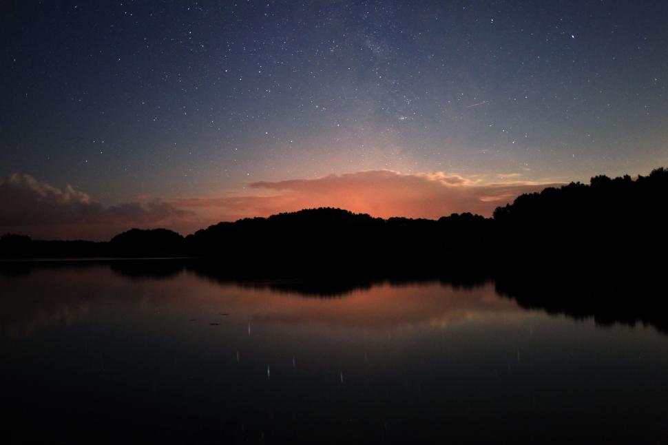 Free Image of Night Sky Reflecting on Water Surrounded by Trees 