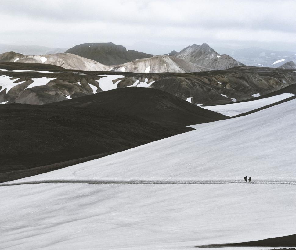 Free Image of Couple Walking Across Snow Covered Slope 