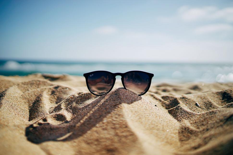Free Image of Sunglasses Resting on Sandy Beach 