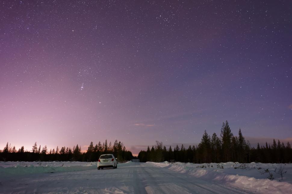 Free Image of Car Driving Down Snow Covered Road Under Purple Sky 