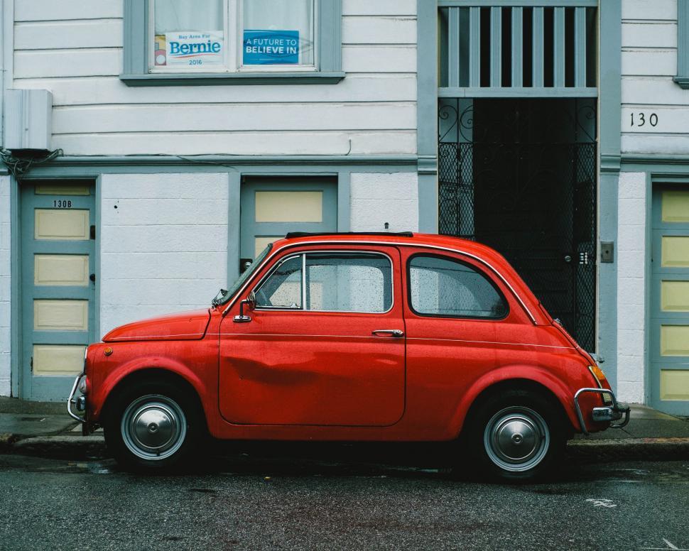 Free Image of Small Red Car Parked in Front of Building 