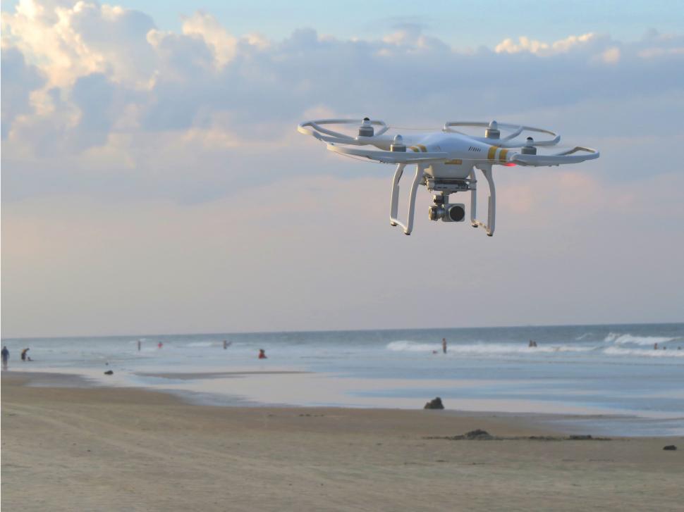 Free Image of Large White Remote Controlled Drone Flying Over Beach 