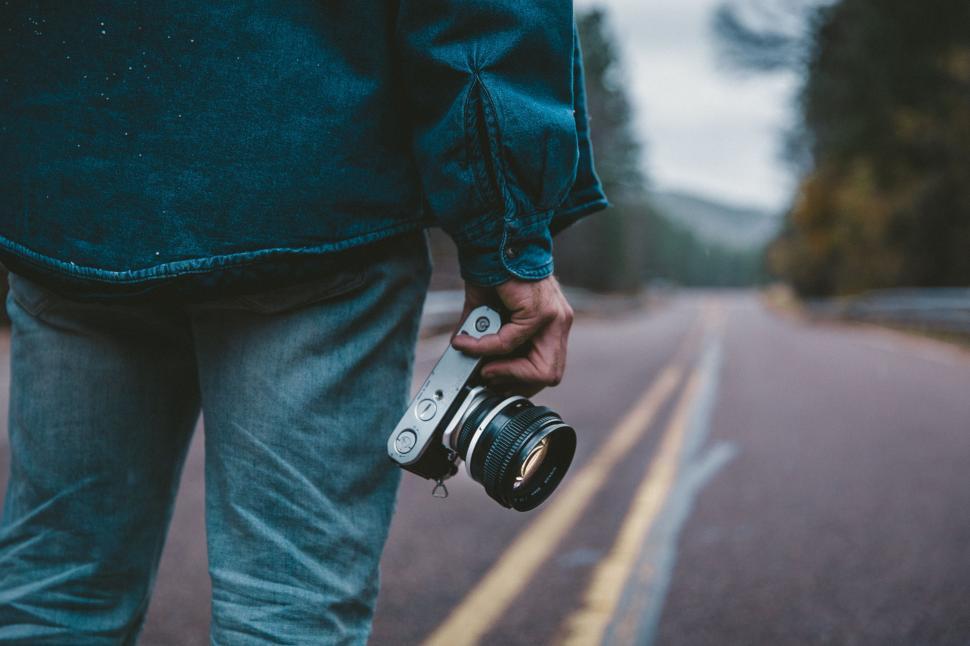 Free Image of Man Holding Camera on Side of Road 