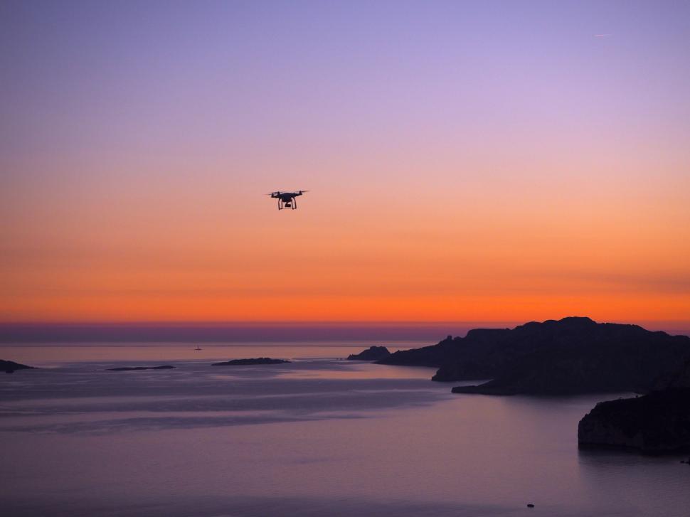 Free Image of A Plane Flying Over a Body of Water at Sunset 