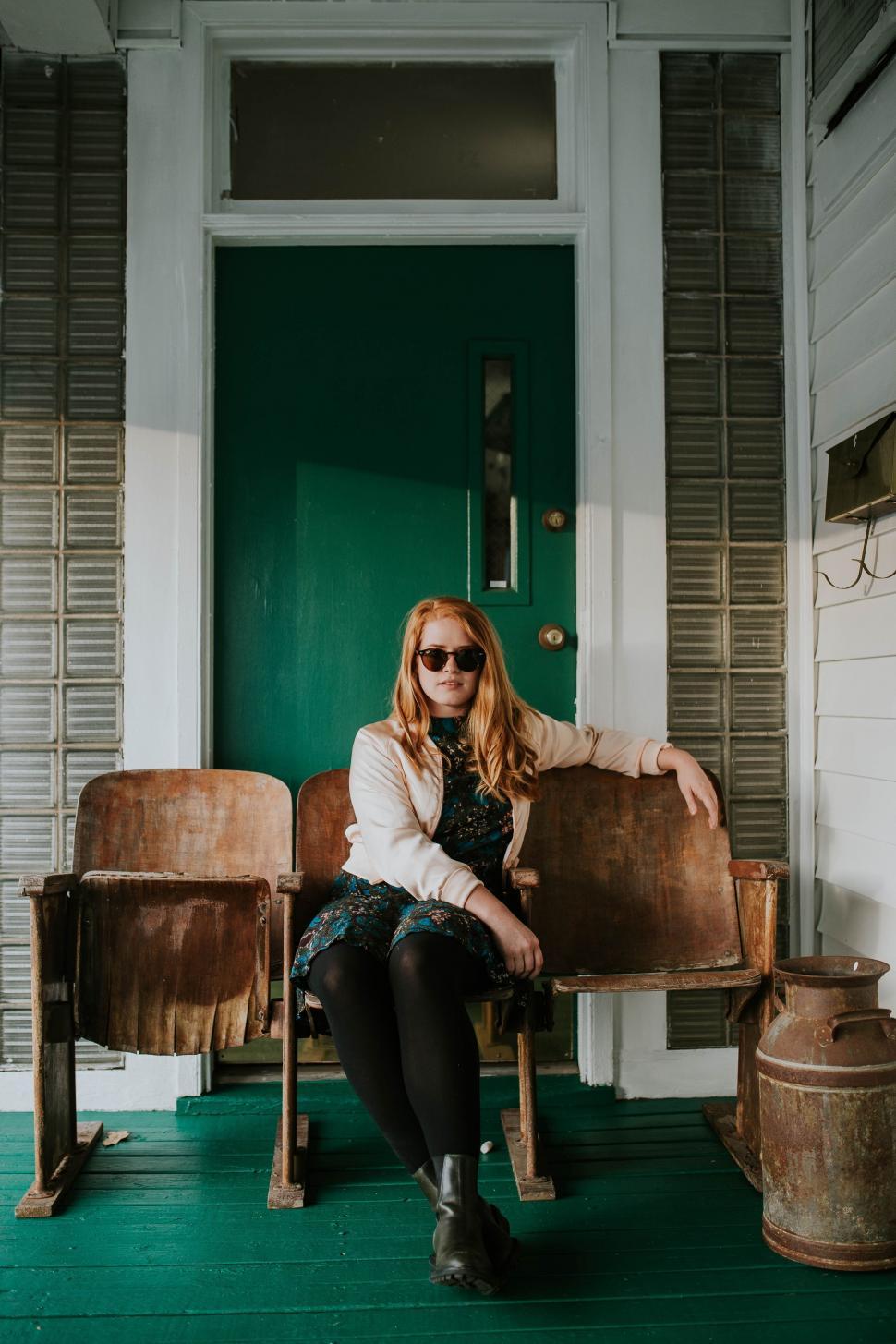 Free Image of Woman Sitting on Chair in Front of Green Door 