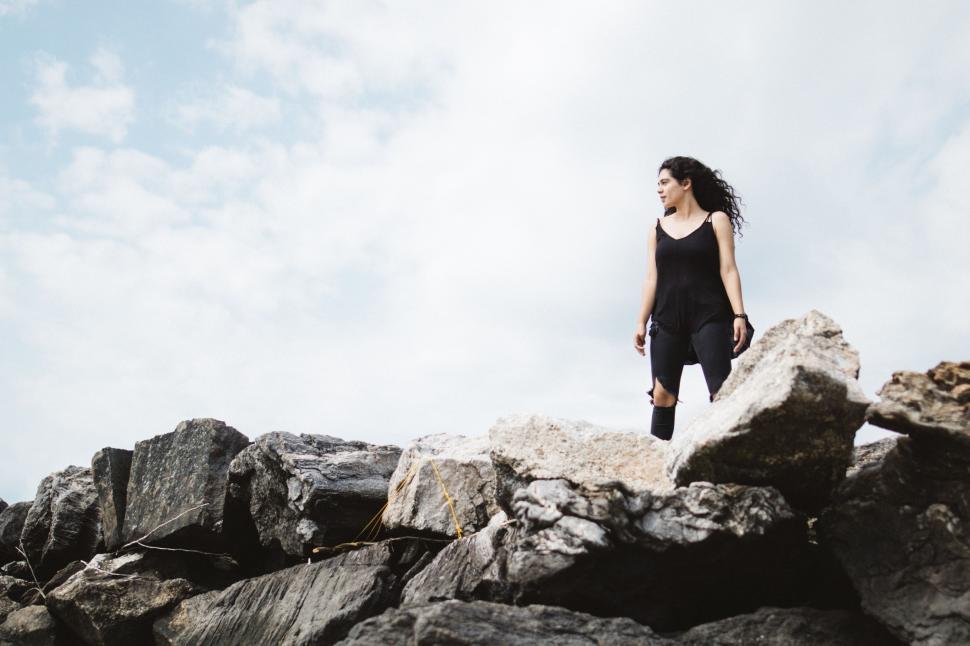 Free Image of Woman Standing on Top of Pile of Rocks 