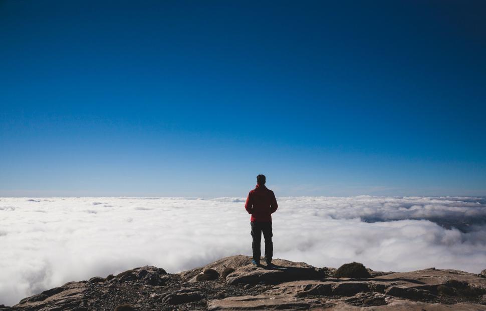 Free Image of Man Standing on Top of a Mountain Above the Clouds 