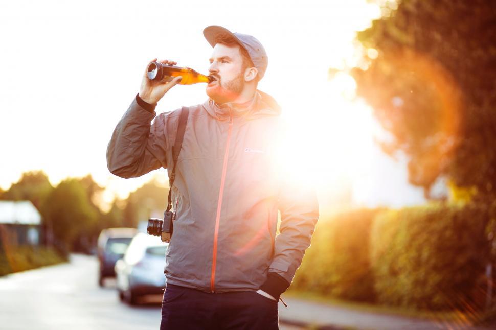 Free Image of Man Standing on Side of Road Drinking Beer 