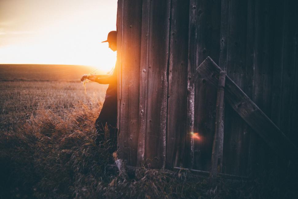 Free Image of Man Standing Next to Wooden Structure in Field 