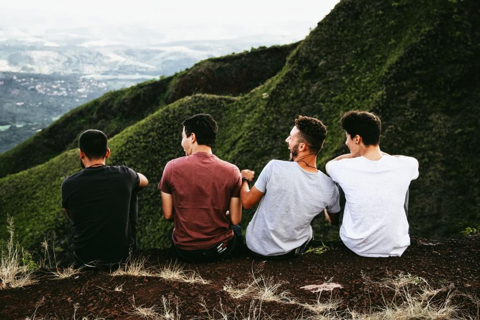 Free Image of Group of Men Sitting on Top of Lush Green Hillside 
