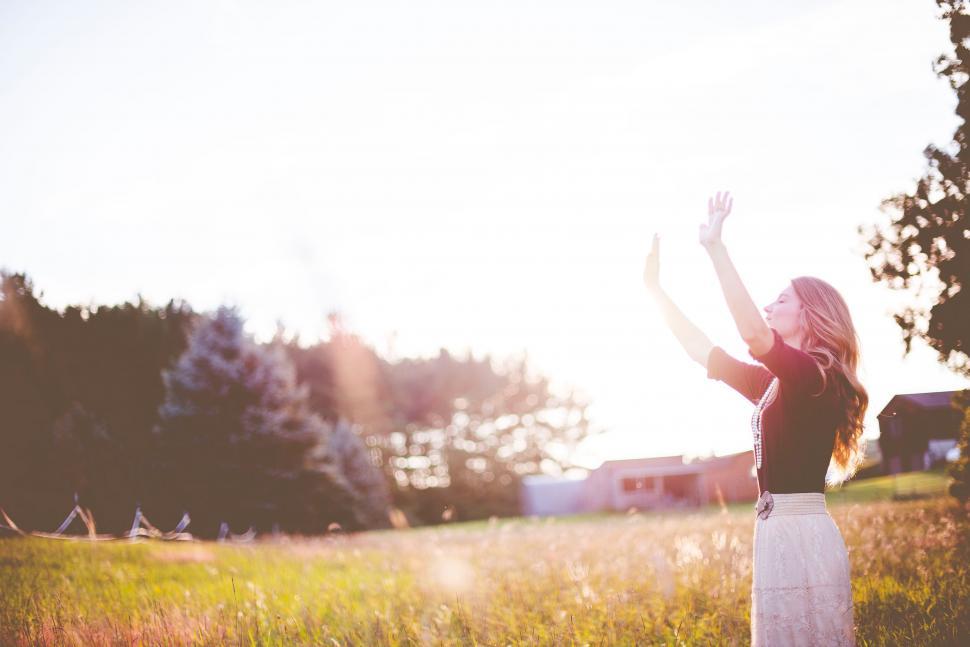 Free Image of Woman Standing in Field With Arms Up 