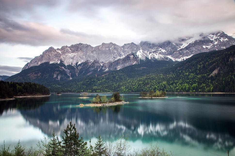 Free Image of Lake Surrounded by Mountains and Trees Under Cloudy Sky 