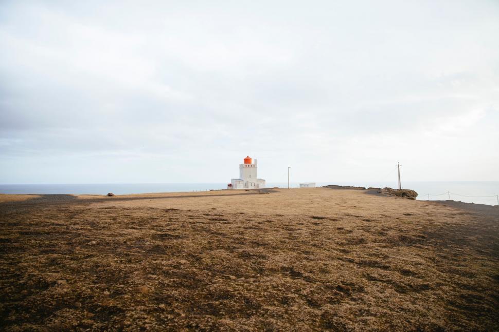 Free Image of Lighthouse Overlooking Hill by Ocean 