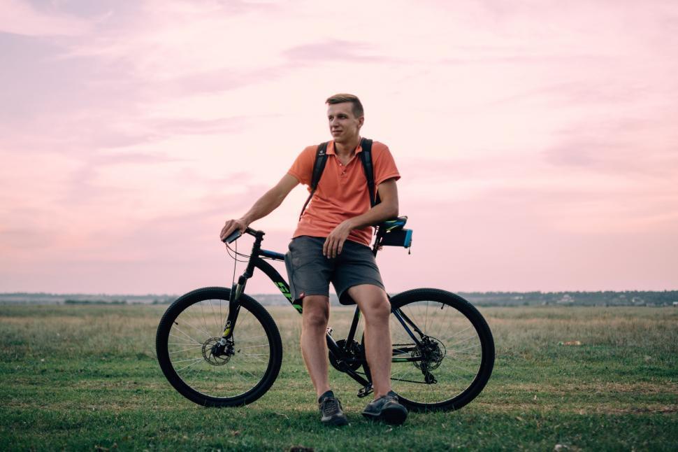 Free Image of Man Standing Next to Bike in Field 