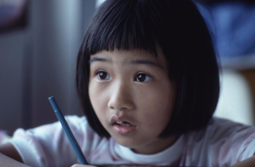 Free Image of Young Girl Sitting at Desk With Pen 