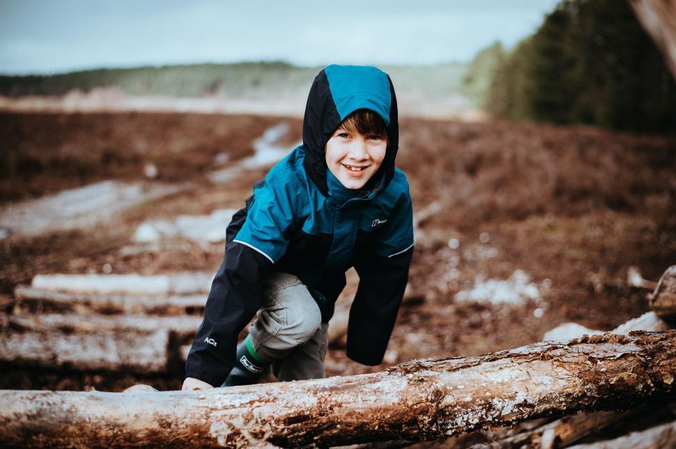 Free Image of Boy in Blue Jacket Climbing Over Log 