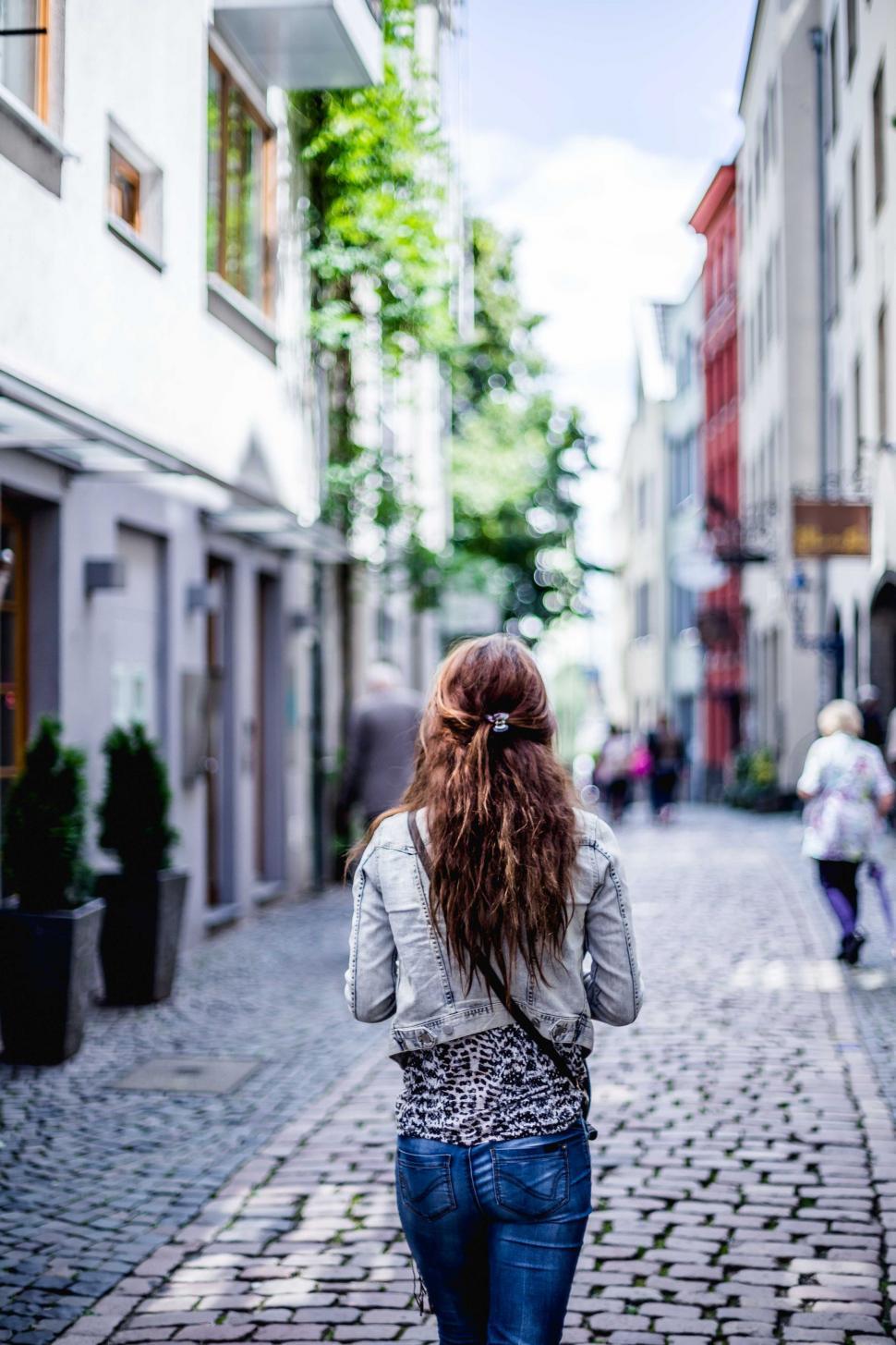 Free Image of Woman Walking Down a Cobblestone Street 
