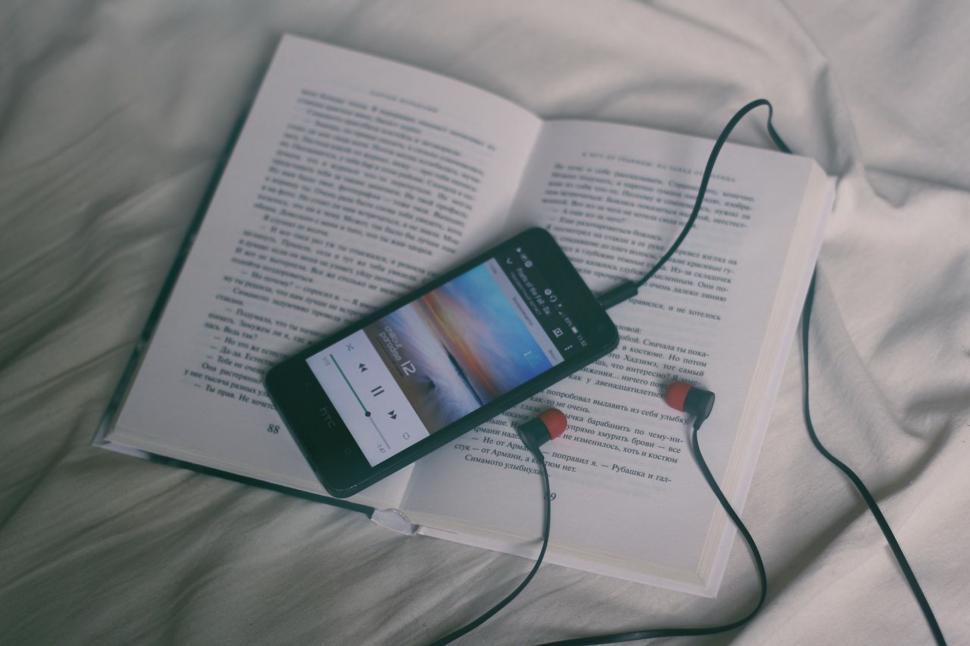 Free Image of Open Book and Headphones on Bed 