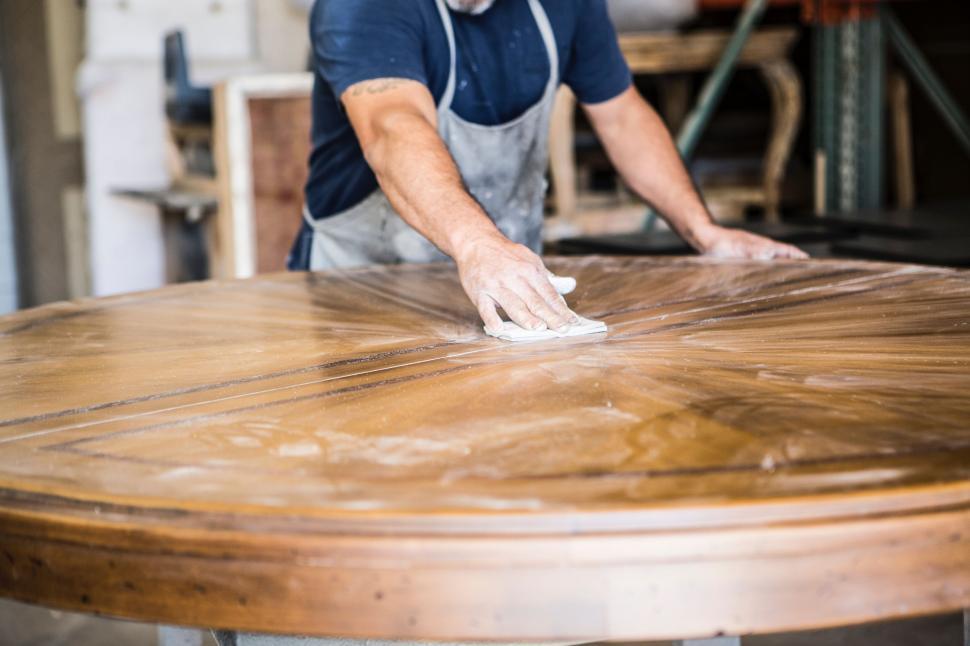 Free Image of Man Wiping Down a Wooden Table Top 