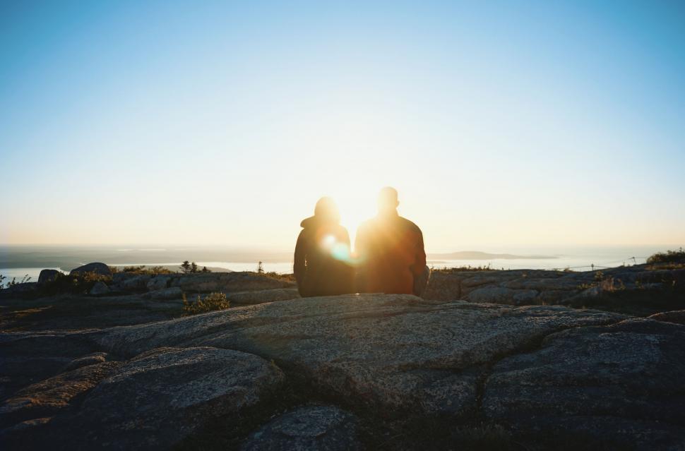 Free Image of Two People Sitting on a Rock Looking at the Sun 