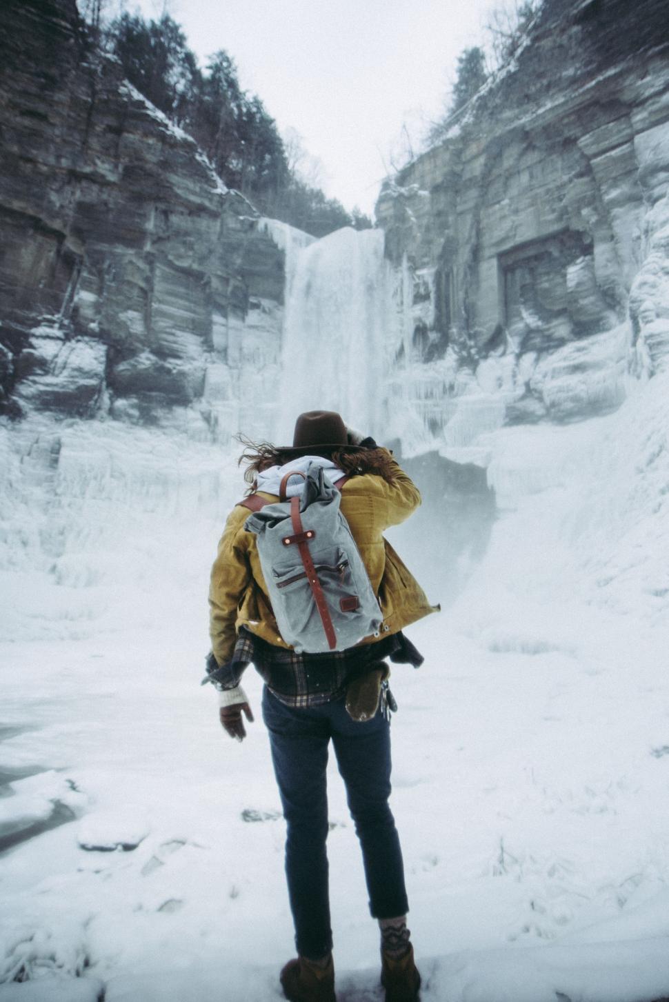Free Image of Person With Backpack Standing in Front of Waterfall 