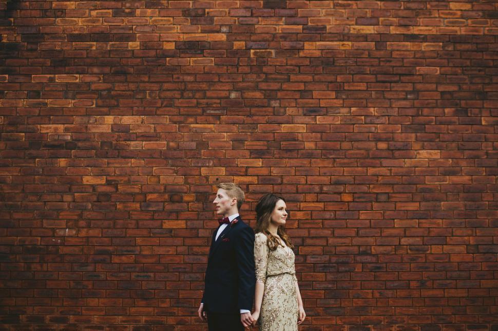 Free Image of Man and Woman Standing in Front of Brick Wall 