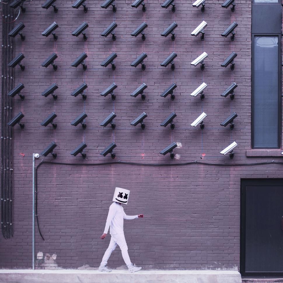 Free Image of Person Walking Past Wall of Cameras 