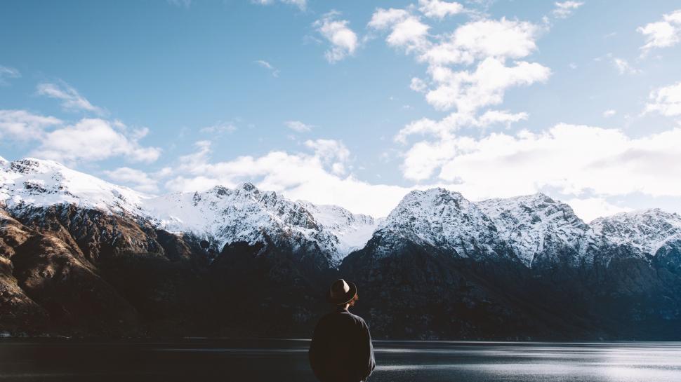Free Image of Man Standing in Front of Lake Surrounded by Mountains 