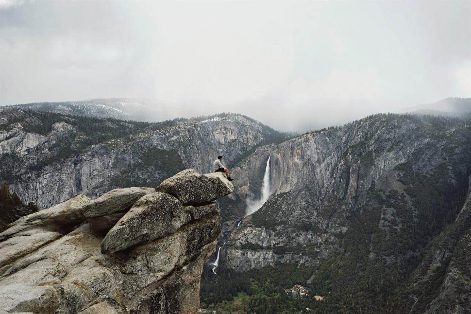 Free Image of Person Standing on Cliff With Waterfall in Background 