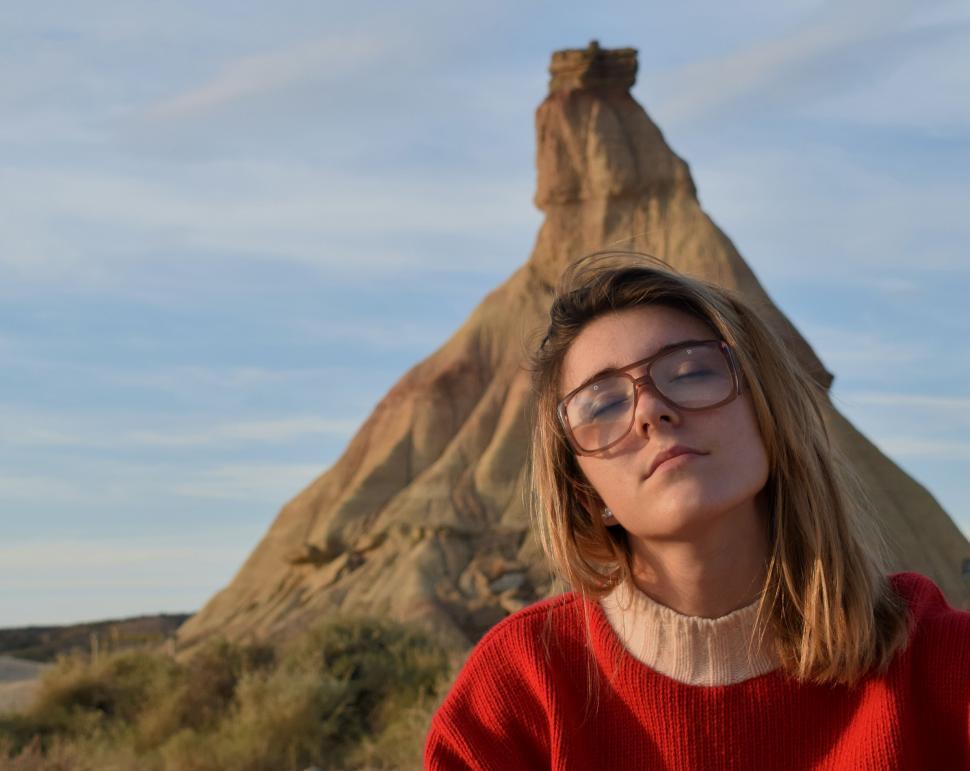 Free Image of Woman With Glasses Standing in Front of Mountain 