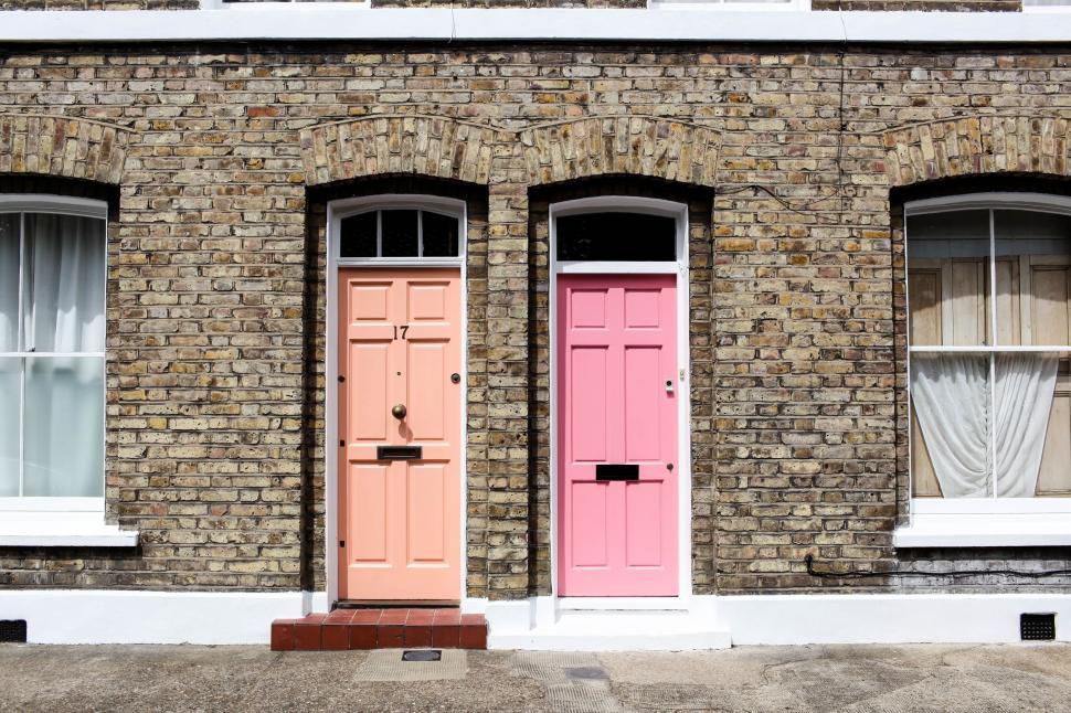 Free Image of Brick Building With Two Pink Doors and Two White Windows 