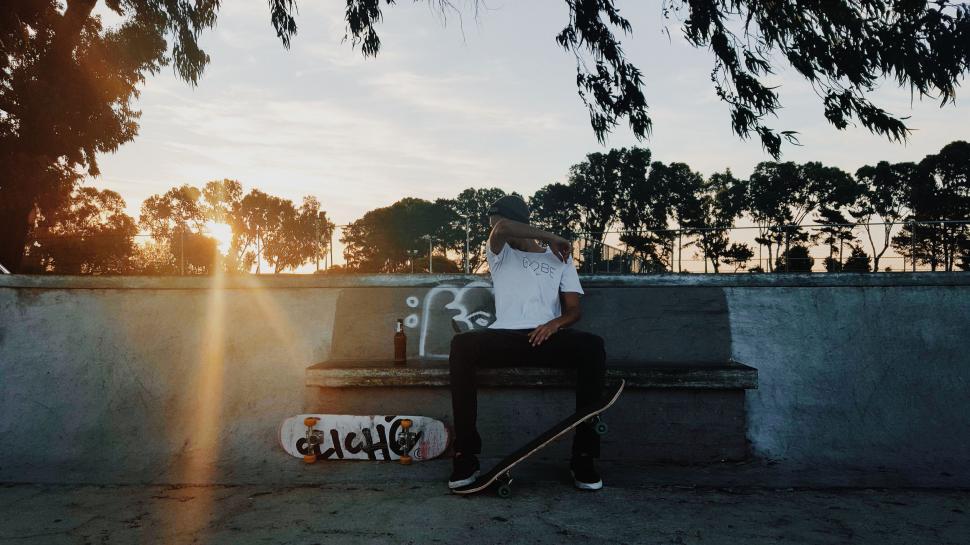 Free Image of Person Sitting on a Bench With Skateboard 