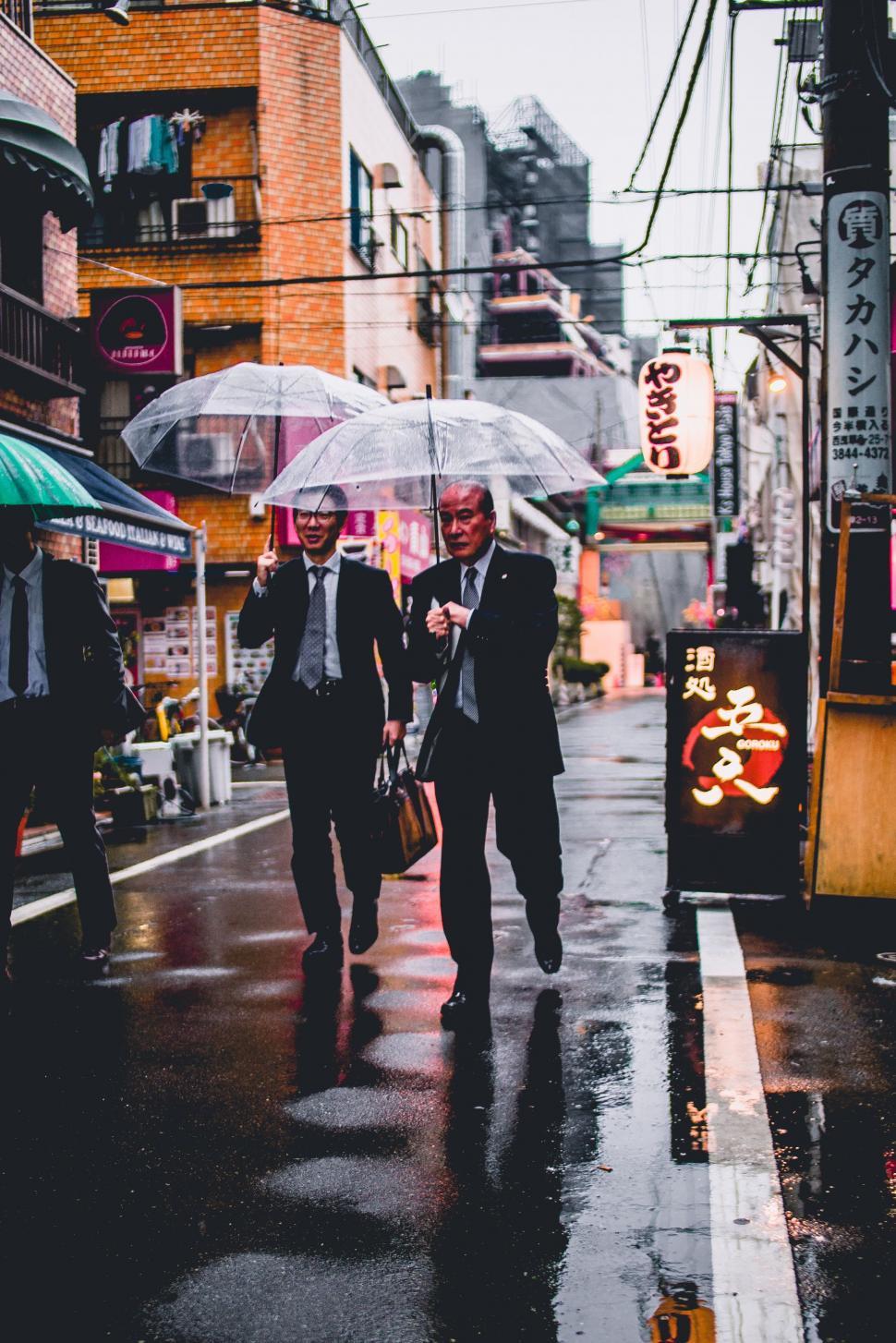 Free Image of Men Walking Down Street Holding Umbrellas 